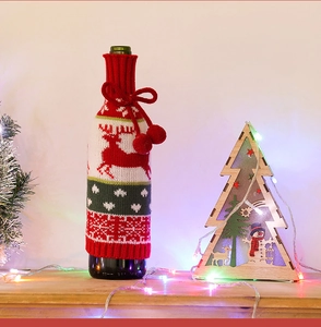 Detail of Christmas wine bottle cover featuring knitted red reindeer and snowflake patterns