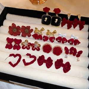 Detailed close-up of red velvet and pearl flower earrings displayed on a white tray