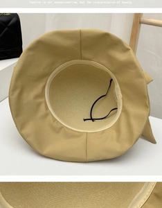 Detail showing the inner structure of a straw sun hat with an adjustable black wind rope