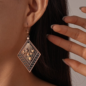 Detail of vintage bronze rhombus earring with woven wire and coconut shell beads on model