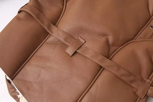 Gros plan sur la texture du manteau en cuir marron avec ceinture et doublure en fourrure