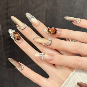 Cat eye press-on nails in amber brown and champagne gold with gemstone and pearl accents