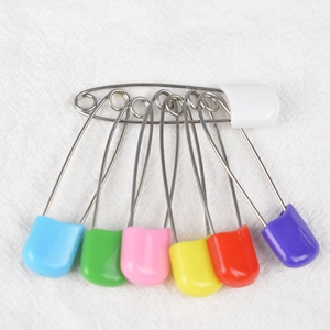 Colorful smiley face baby safety pins in assorted sizes on white cotton fabric