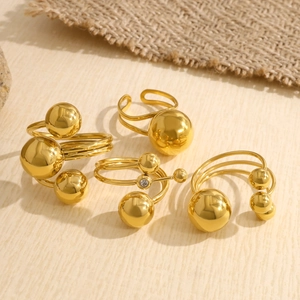 Detail of four gold-plated spherical rings with polished finish and zircon accents
