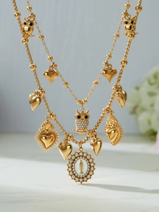 Detail of gold zircon layered necklaces featuring owl, heart, and religious relief charms