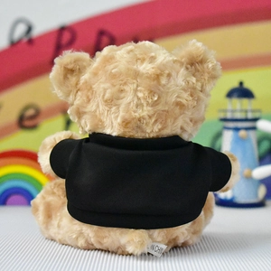 Detail showing the back of a brown plush teddy bear wearing a black t-shirt.
