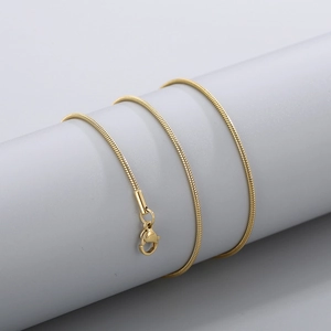 Detailed view of a golden snake bone chain necklace with lobster clasp on a display stand