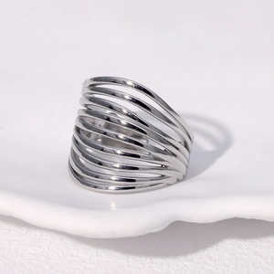 Bague ouverte géométrique multicouche argentée minimaliste sur plateau céramique