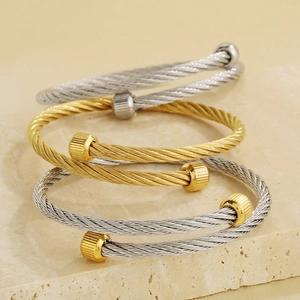 Macro shot of stacked gold and silver twisted cable bracelets with industrial end caps