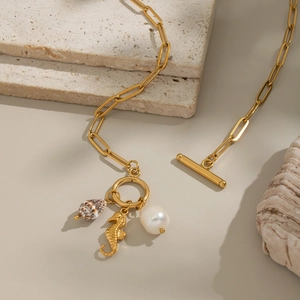 Detailed shot of gold necklace featuring seashell, seahorse, and pearl charms with toggle clasp