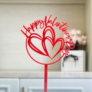 Macro view of a red acrylic Happy Valentine's Day cake topper with two intertwined hearts