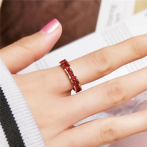 Elegance rose gold eternity ring with red crystals on a model hand with soft background
