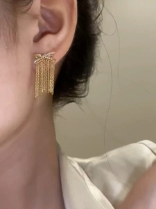 Detail von 14k vergoldeten Schleifenohrringen mit Quasten und funkelnden Zirkonia