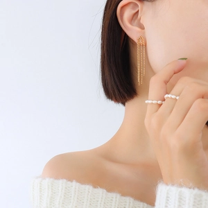 Boucles d'oreilles pompons en perles dorées avec bagues en perles portées par modèle