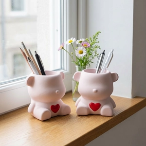 Pots de rangement ours roses avec cœurs rouges et crayons sur un bureau chaleureux