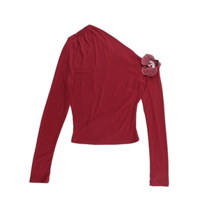 Detail of red one-shoulder long sleeve top featuring a 3D floral accent on the shoulder