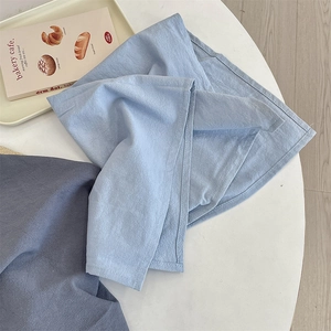 Detail of solid color cotton linen placemats with fine edge stitching on white table