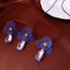 Détail du collier fleur et boucles d'oreilles avec cristaux violets sur tissu en soie