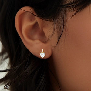 Detailed view of heart-shaped gold stud earring with sparkling cubic zirconia on ear