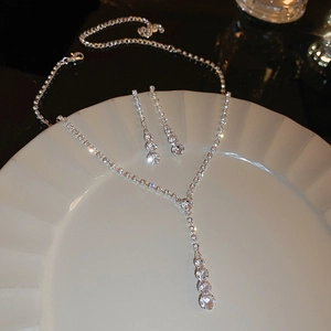 Détail d'un ensemble collier nœud en strass argenté et boucles d'oreilles perles
