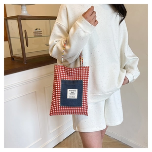 Détail du grand sac cabas à carreaux rouges et blancs avec poche en jean par mannequin
