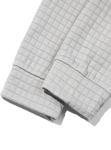 Detailed macro view of the light grey textured waffle knit fabric and ribbed cuff finish