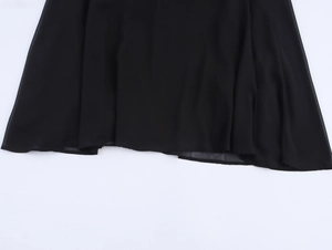 Dettaglio dell'orlo del vestito in chiffon nero con cuciture precise e trama del tessuto