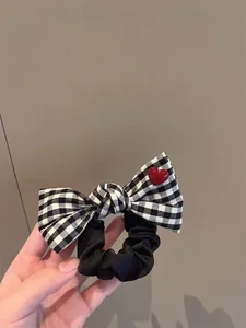 Detail of checkered bow hair scrunchie with red heart charm on soft fabric band