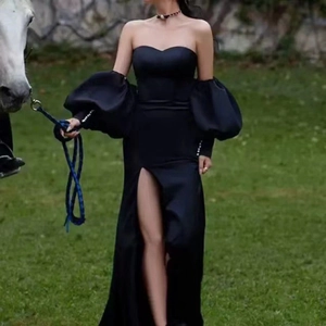 Detail of elegant black off-shoulder satin gown with voluminous puff sleeves and side slit