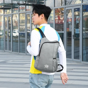 Gray lightweight foldable hiking backpack for outdoor sports on model with mountain logo