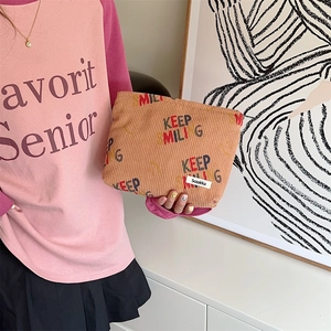 Detail of corduroy makeup bag with Keep Smiling print and brand label on khaki fabric