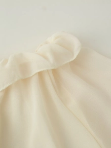 Dettaglio dell'elegante bordo a volant in chiffon su un set a due pezzi bianco crema