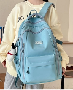 Close-up of sky blue durable nylon backpack featuring multiple pockets and dog pendant