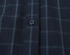 Detail of dark blue plaid poplin shirt showing the button and fine stitching