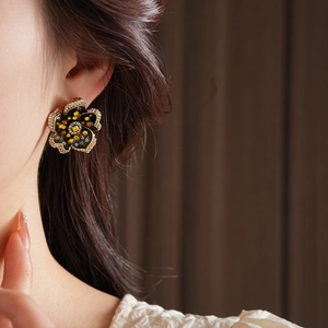 Macro shot of vintage floral stud earrings with yellow crystals and golden trim detail