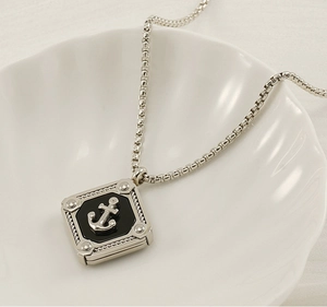 Macro shot of silver anchor pendant necklace with black base on white shell plate