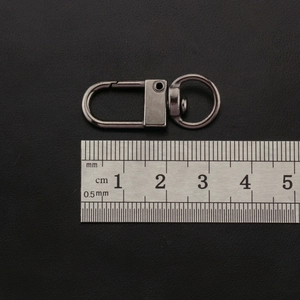 Macro view of 35mm gun black swivel lobster clasp with a scale for size reference