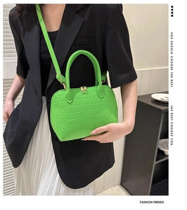 Detail of neon green shell bag with crocodile texture and golden zipper hardware