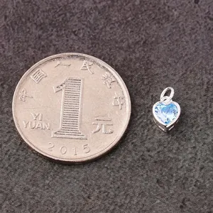 S925 silver heart pendant with sky blue cubic zirconia next to a coin for size reference