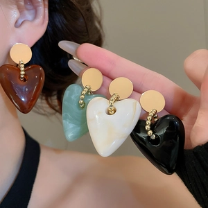 Detail of heart-shaped acrylic earrings in multiple colors showing marble texture and shine