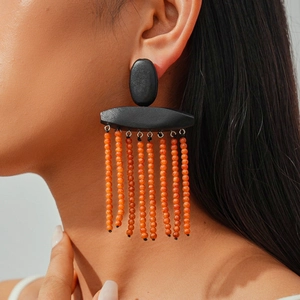 Close-up of ethnic style tassel earrings with black wood and orange beaded strands