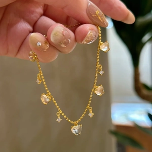 Close-up of golden tassel bracelet with heart charms and sparkling diamond pendants