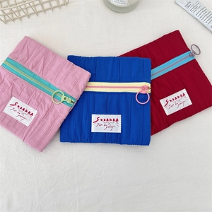 Detailed view of quilted makeup bags in pink, navy and red with contrast zippers