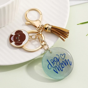 Detail showing dog mom printed resin tag and brown poodle enamel charm on golden keychain