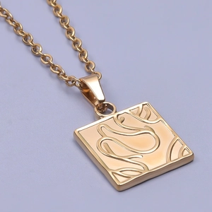 Macro view of gold square pendant with abstract engraved texture on 18k gold plated chain