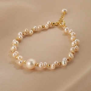 Vista macro di bracciale di perle intrecciate con perline dorate su elegante raso