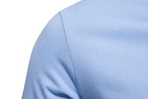 Gros plan du polo en coton piqué bleu clair montrant la texture et les coutures fines