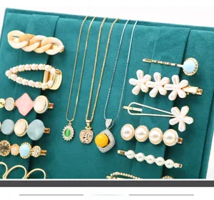 Detail view of various hair clips and necklaces on a teal faux suede display board