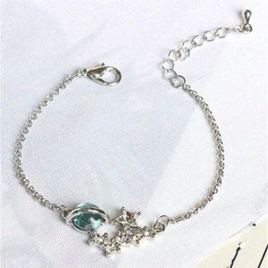 Detailed shot of silver bracelet featuring blue planet and star charms on white fabric