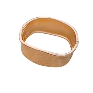 Minimalist hammered gold bangle with an elegant textured surface and side hinge closure